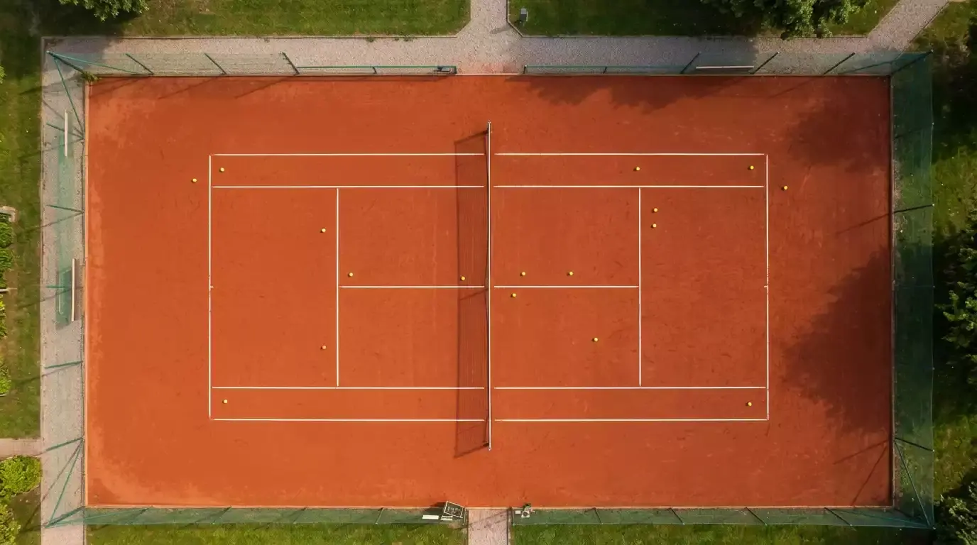 Mehrere Tennisbälle verstreut auf einem Sandplatz als Symbol für die Gesamtzahl der Spiele in einem Match