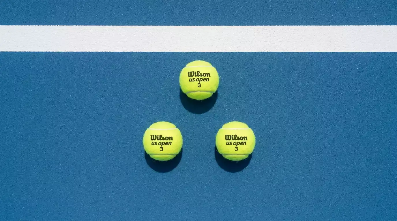 Drei Tennisbälle in einer dreieckigen Anordnung auf einem Hartplatz als Symbol für Systemwetten mit mehreren Auswahlen